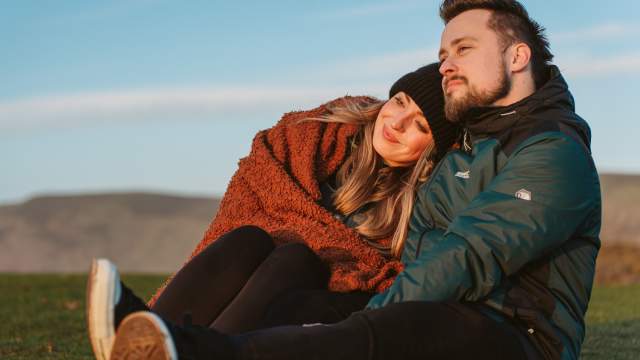 A couple (man and woman) in winter clothes watching a sunset.