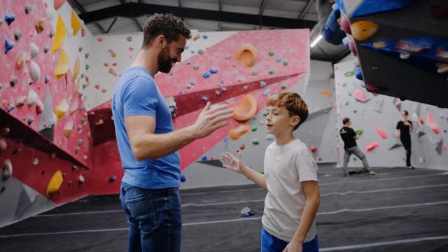 A father and son going to low-five each other in The Climbing Hangar, Llansamlet