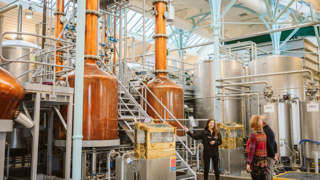 Tour guide explaining the penderyn distillery to a couple