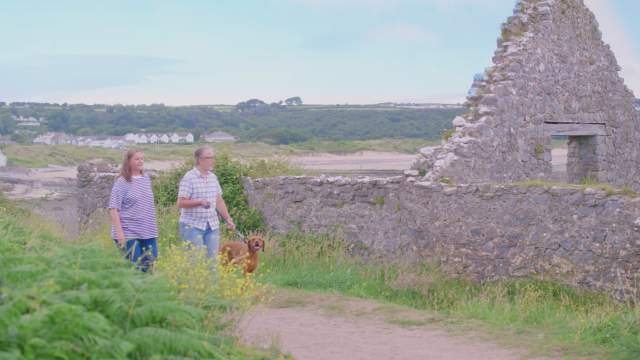 A couple walking their dog by the salt house, Port Eynon.