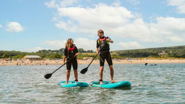 Two people paddleboarding in Gower