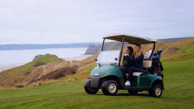 Two ladies driving a golf cart at Pennard Golf Course
