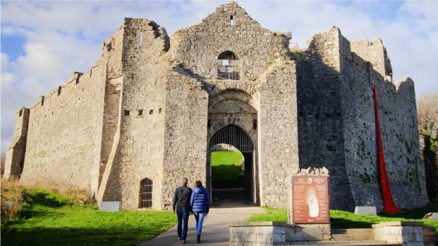 Two people walking into Oystermouth Castle.