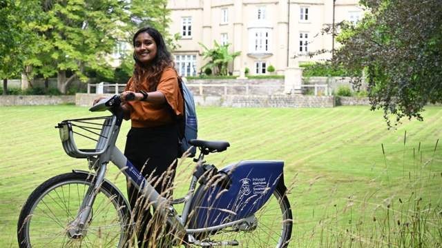A young ladies standing with a Swansea University Cycles bike