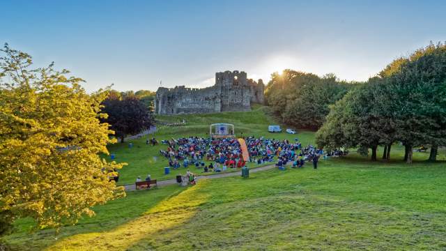 theatre performance with crowd watching on with oystermouth castle in the background at sunset