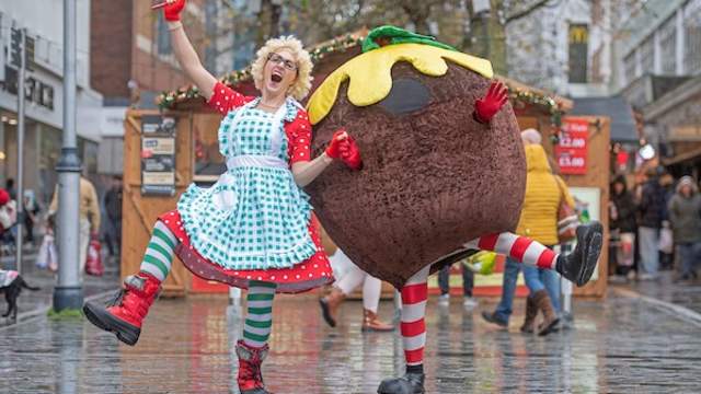 A man dressed as a panto dame and a person in a Christmas pudding costume.