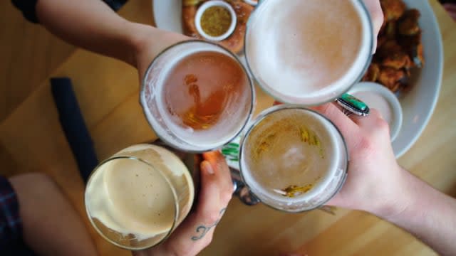 4 patrons holding their beer up in a toast at a brewery in Salt Lake City
