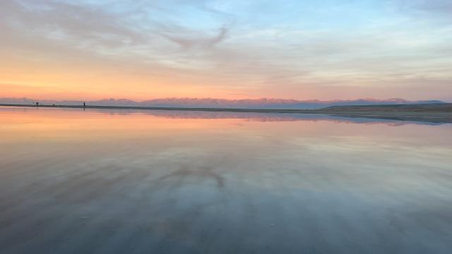 Great Salt Lake at sunset with the mountains a light pink and the sunset and sky reflected in the lake