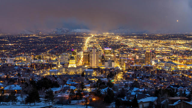 Aerial view of Salt Lake at night looking south down main street from above the capitol building. The city is lit up with yellow lights.