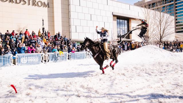 Women on horse drags man skiing over a man-made ski jump. The man is being pulled by rope by the woman on a horse on West Temple Street in front of Nordstrom's in City Creek Center.