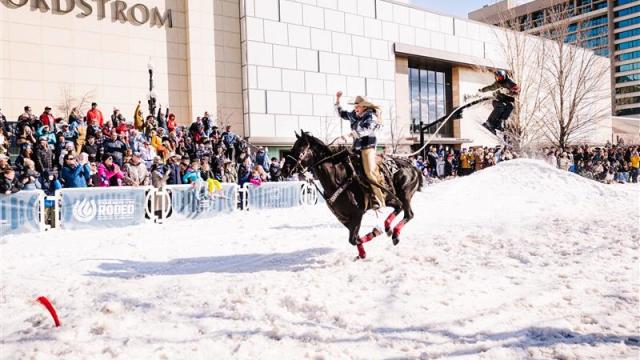 Two people skijoring in front of Nordstroms in Downtown Salt Lake