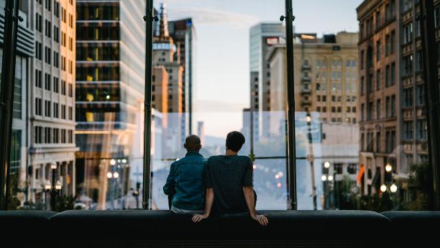Two people sitting on a bench in the walkway at City Creek over main street looking down Main street