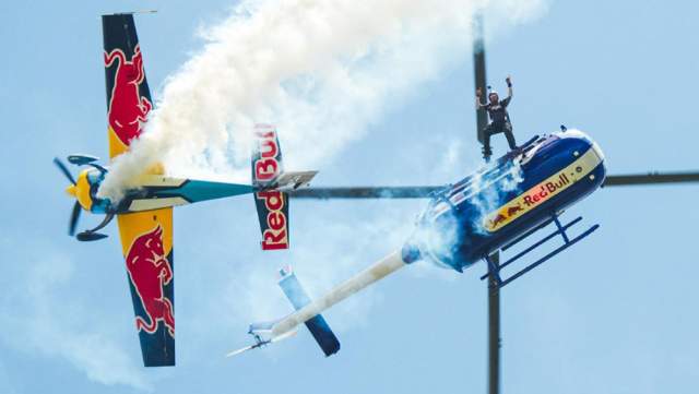 an airplane and helicopter of the red bull air force, performing stunts in flight