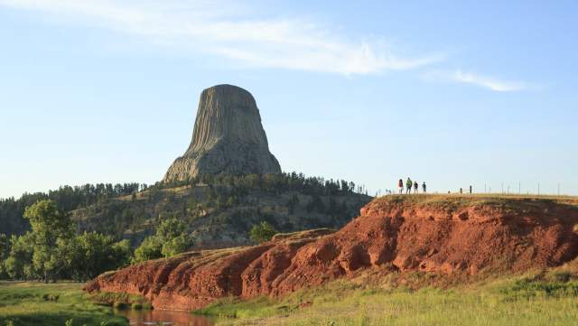 Hiker walking along a trail surrounded by lush greenery in Wyoming at sunrise