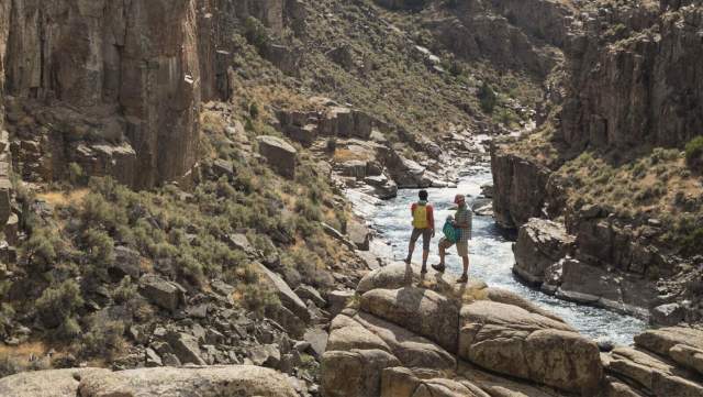 Hiker on a rocky trail over looking a vast mountain landscape in Wyoming