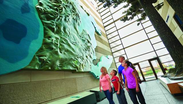 Family looking at an art piece of topographical Michigan
