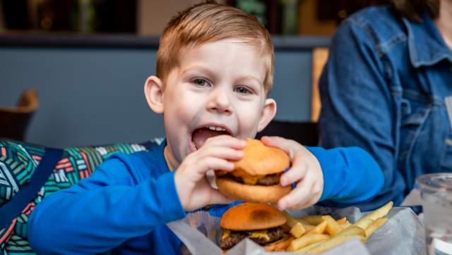 Young boy biting into a small burger at Midtown Brewing.
