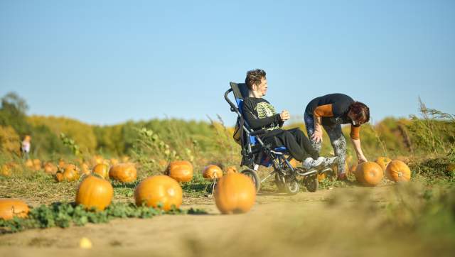 A wheelchair user and a friend picking pumpkins at Uncle John's Cider Mill