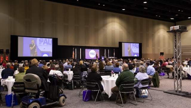 A group of tables and large screens at the Lansing Center during a conference