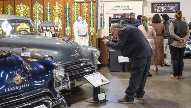 Man taking a photograph of an Oldsmobile Automobile at R.E. Olds Transportation Museum