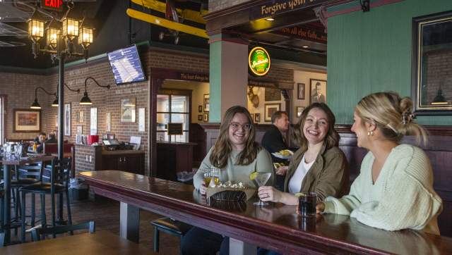 Three people laughing and enjoying drinks