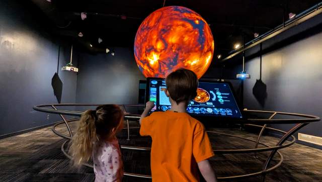 Two kids looking at a monitor of the sun in the sphere room at the MSU Museum