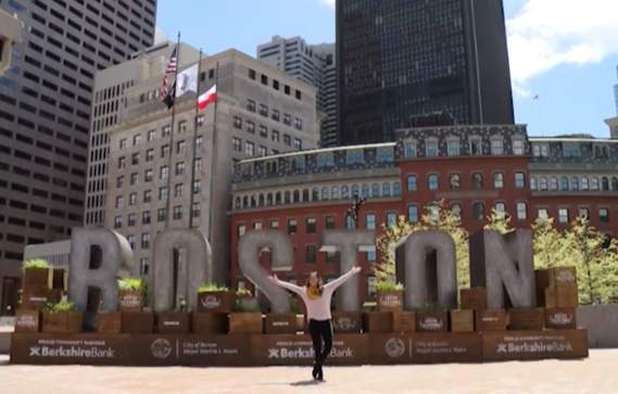 Woman standing in front of large letters reading "Boston"