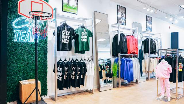 A retail shop with tshirts that read: City On My Chest are set out alongside a basketball hoop in a mall storefront