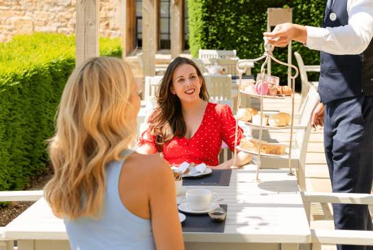 Two people enjoying afternoon tea outdoors at Ellenborough Park Hotel & Spa in Cheltenham