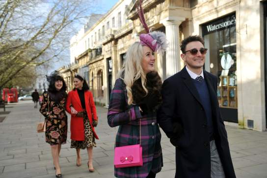 Friends dressed in racewear walking down The Promenade in Cheltenham.