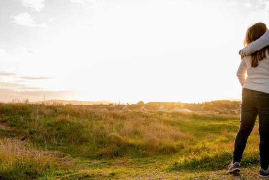 Two people standing outside watching the sun set