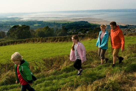 Family walking in the countryside with the sea in the background