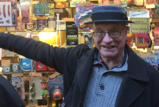 Local tour guide standing beside Hulls colourful vintage joke shop display filled with 4 novelty items and quirky memorabilia