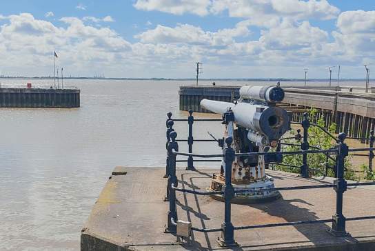 World War One Navel Gun  overlooking The Humber estuary under a bright blue sky with large white clouds