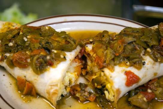 An enchilada topped with freshly-roasted hatch green chilies.