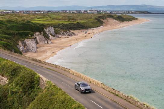 A car driving along the road with Whiterocks Beach in the background