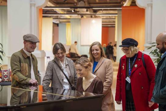 Visitors watching a performer at the piano