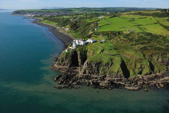Aerial shot of Blackhead Lightkeepers House with the sweeping coast in view.