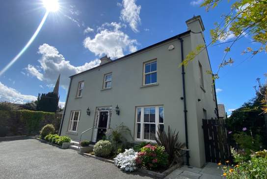 Exterior shot of Bramley House, a self-catering property in County Down.  There are plants outside the front of the house, and the sun is shining with blue skies.