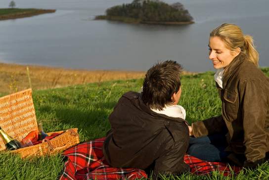 Couple enjoying a picnic, Lough Erne Resort with lake in background