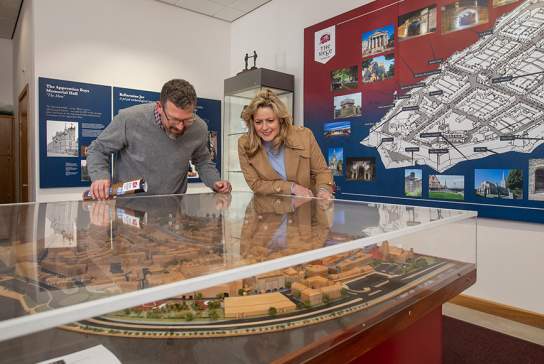 Two visitors enjoying the exhibitions at the Siege Museum in Derry-Londonderry, looking over a glass case with a model village inside