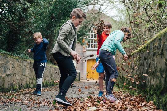 Children playing in the Autumn leaves at the Ulster Folk Museum.