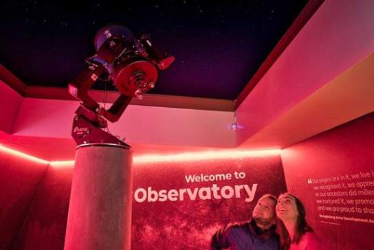 A couple looking up at a telescope at the OM Dark Sky Observatory