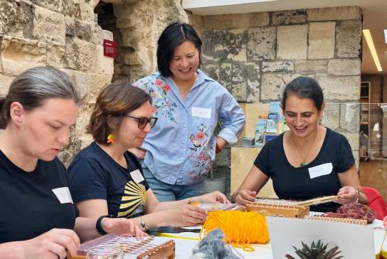 Group of women weaving on small looms at God's House Tower as part of a women led workshop