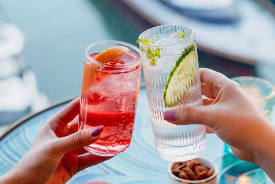 People clinking cocktails together at HarBAR on 6th rooftop bar