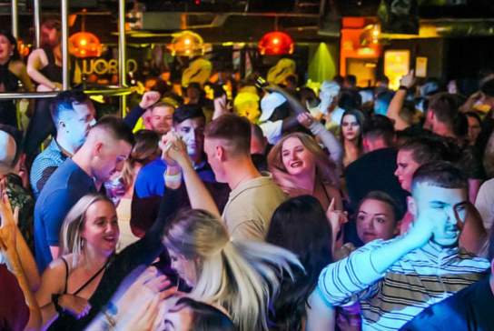Club goers dancing under a disco ball on the dancefloor at Popworld