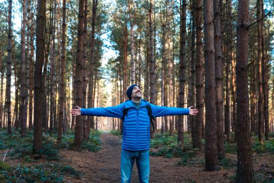 Man in forrest with wide open arms