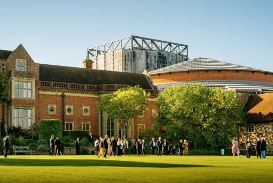 Image of external of Glyndebourne Opera with green lawn and people milling around