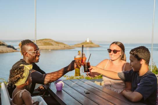 Family toasting their glasses with coast in the background