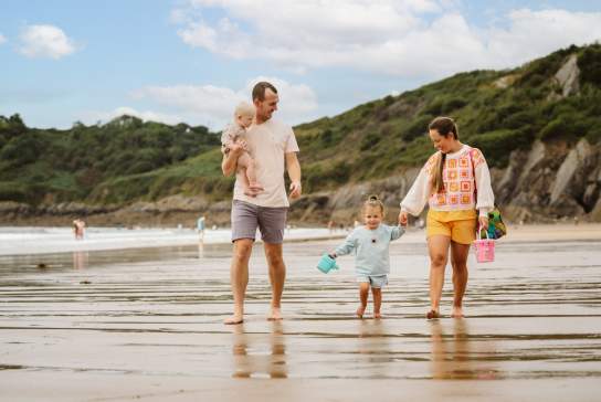 young family walking along the beach with bucket and spades